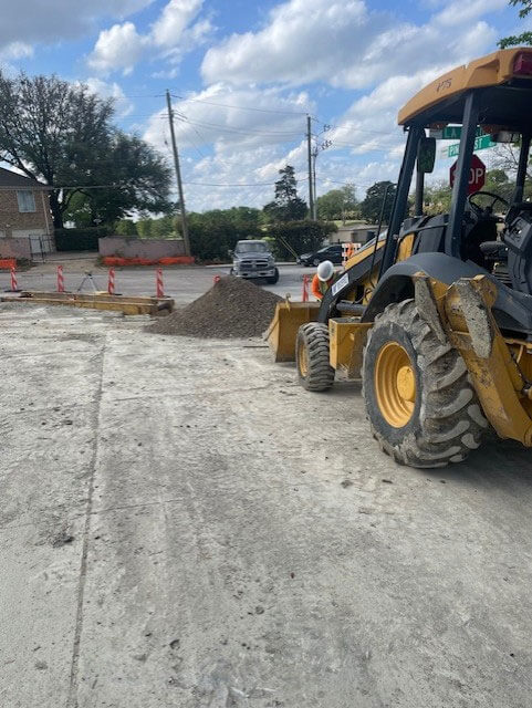 Construction area with front loader and gravel pile partially obstructing the roadway near the entrance.